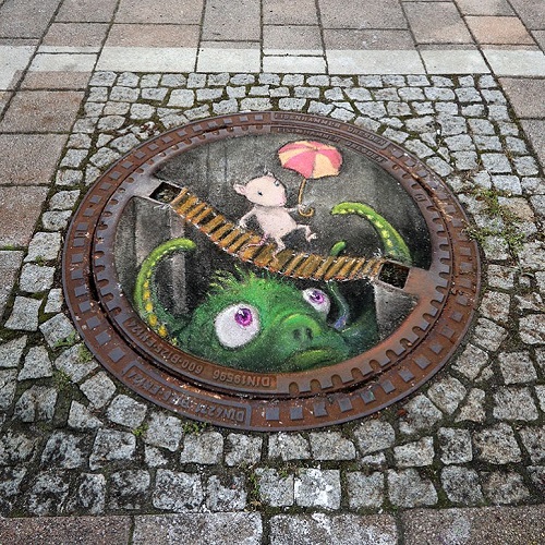 Rysunek Davida Zinna, studzienka kanalizacyjna jako street art. Przez take studzienki wykonujemy na prace WUKO polegające na czyszczeniu kanalizacji